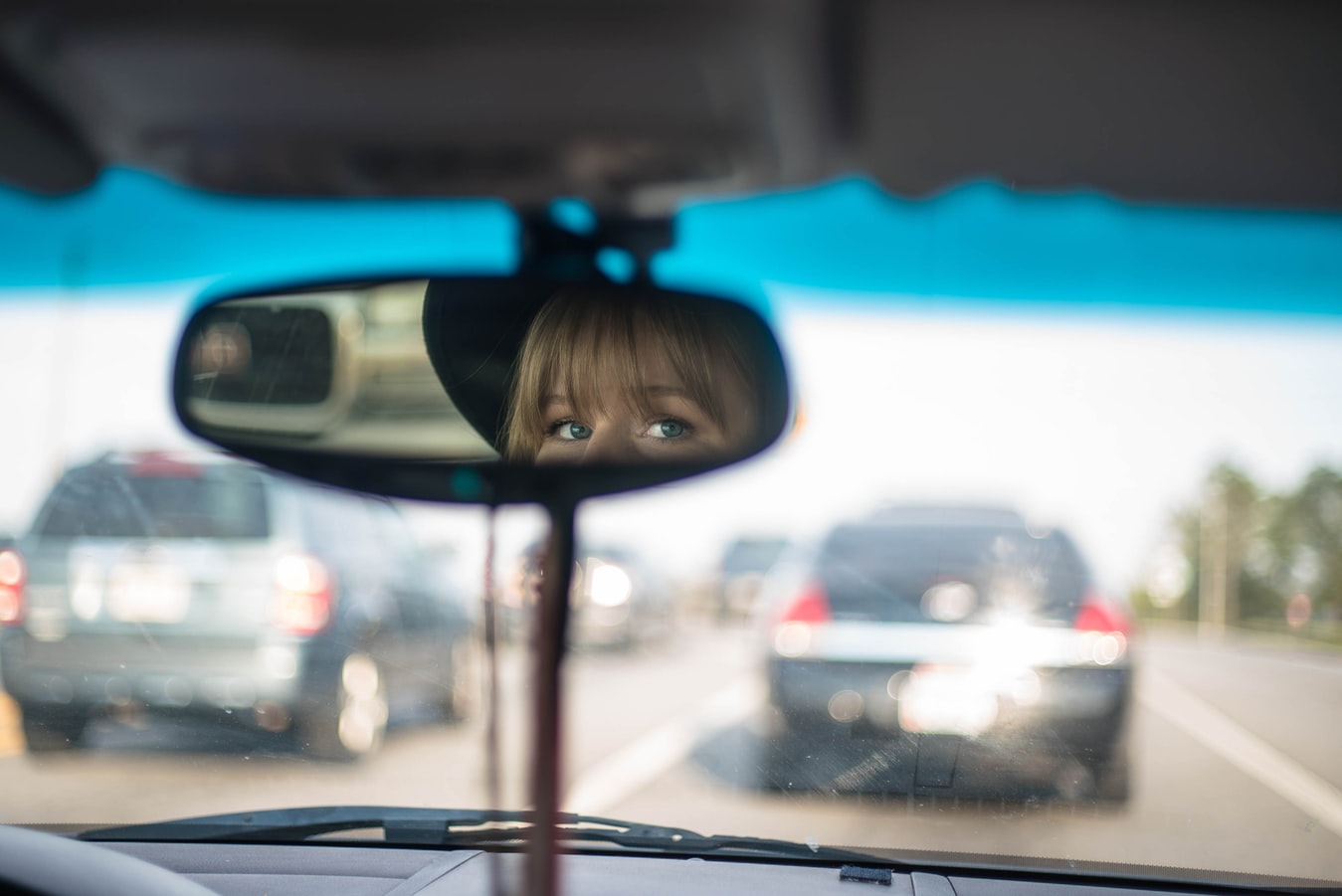 A young woman looking out of her rear view mirror
